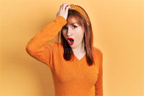 Redhead Young Woman Wearing Casual Orange Sweater Surprised With Hand On Head For Mistake
