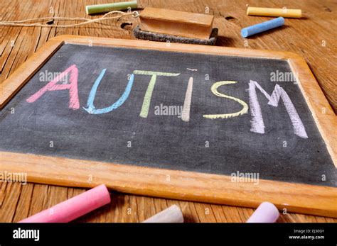 The Word Autism Written With Chalk Of Different Colors In A Chalkboard