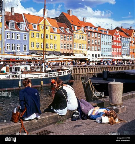 Nyhavn Harbour Copenhagen Denmark Young Women Relaxing On The Quay Quayside Canal Harbor