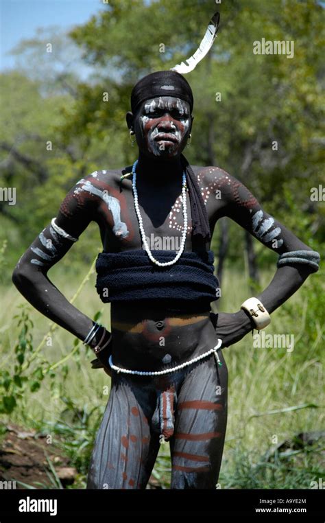 Naked Man Of The Mursi People Wearing A Feather On His Head And Painted Skin From His Face To