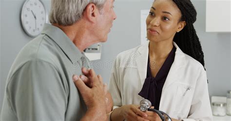 Black Woman Doctor Listening To Elderly Patient Breathing Stock Image