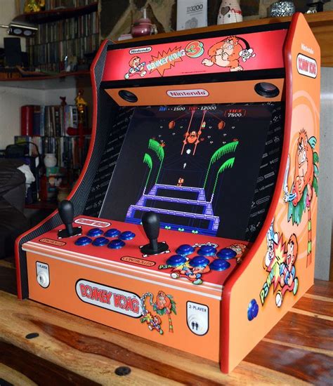 An Orange Arcade Machine Sitting On Top Of A Wooden Table