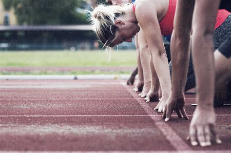 Runners Poised At Starting Line On Track Stock Photo