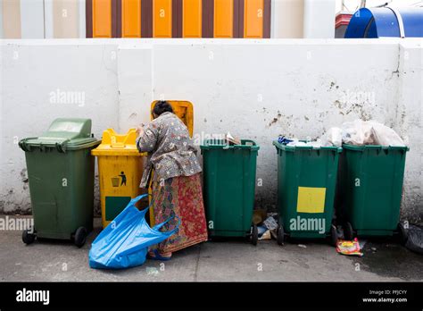 Homeless Woman Is Searching The Trash In A Trash Bin On Street Stock