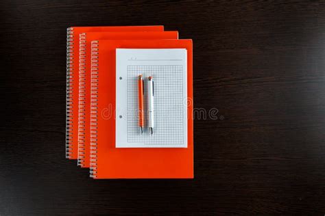 White Sketchbook And Orange Notebooks Lying On A Dark Brown Wooden