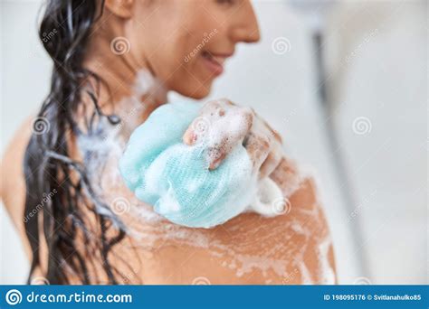 Smiling Young Woman Using Exfoliating Loofah While Taking Shower Stock