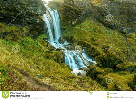 Long Exposure Of A Small Waterfall Running Through A Green Moss Stock