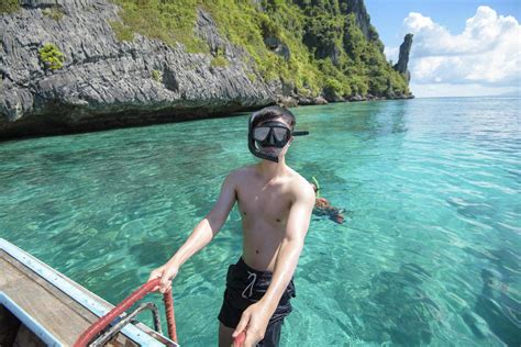 an active man on thai traditional longtail boat is ready to snorkel and dive phi phi islands