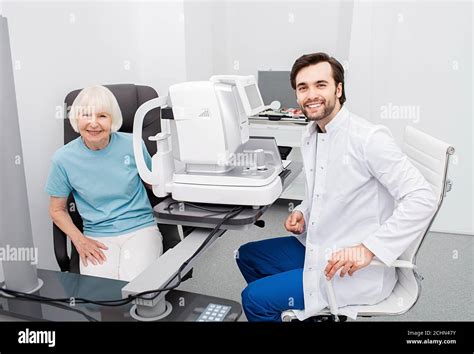 Smiling Optometrist With His Senior Patient Friendly Looking At Camera