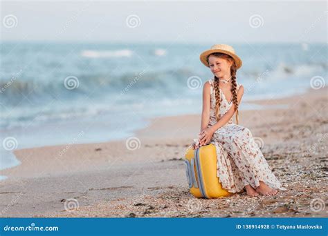 Uma Menina Senta Se Em Uma Mala De Viagem Amarela Na Praia Foto De Stock Imagem De Tenha