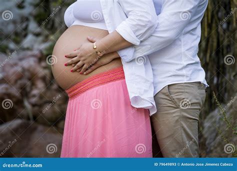 man embraces the belly of his pregnant wife stock image 79649893