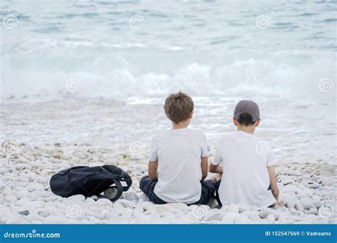 Two Boys Sitting Next To Each Other On The Beach By The Sea Stock Image Image Of Coast Ocean