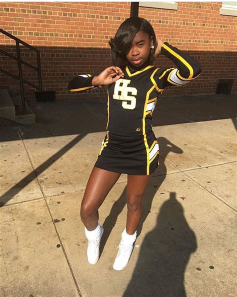 A Woman In A Cheerleader Uniform Posing On The Sidewalk With Her Hands