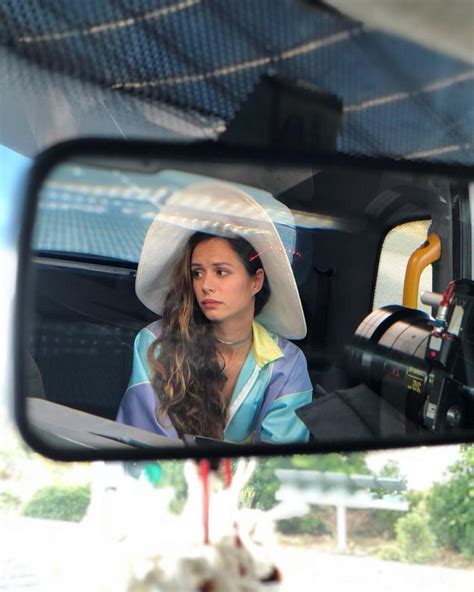 A Woman Wearing A White Hat Is Seen In The Rear View Mirror Of A Vehicle