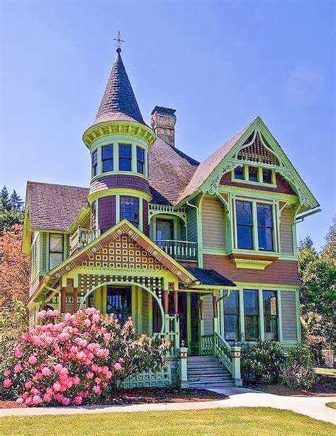 An Old Victorian Style House With Pink Flowers In The Foreground And