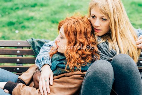 Two Young Beautiful Caucasian Redhead And Blonde Women Friends Sitting