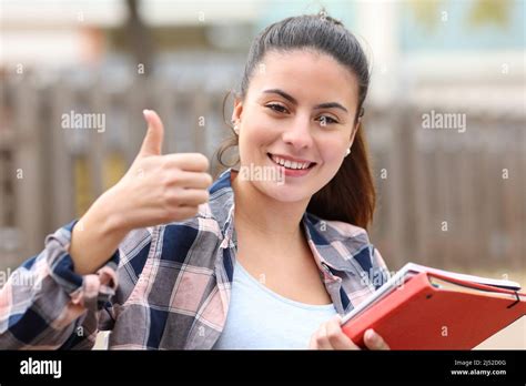 Front View Portrait Of A Happy Student Gesturing Thumbs Up In A Park