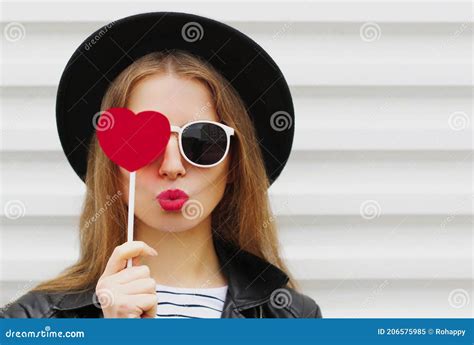 Beautiful Young Woman Covering Her Eyes With Red Heart Shaped Lollipop Blowing Red Lips Sending
