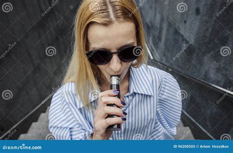 beautiful girl in glasses with pleasure smokes a vapeday outdoor stock image image of liquid