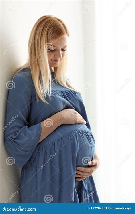Mujer Embarazada Hermosa Cerca De La Pared En Sitio Ligero Imagen De