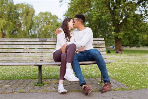 Young Couple On Park Bench Kissing Stock Photo Dissolve