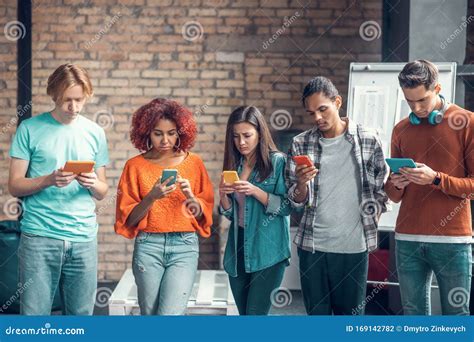 Students Addicted To Social Media Standing And Using Their Smartphones