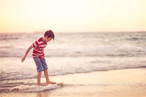 Young Boy Riding A Skim Board At The Beach At Sunset By Stocksy