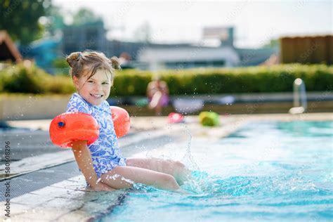 Fotka „little Preschool Girl With Protective Swimmies Playing In Outdoor Swimming Pool By Sunset