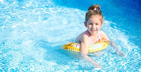 Смешная маленькая девочка плавание в бассейне Премиум Фото