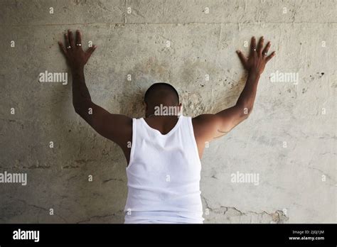 Hands Up And Spread Em Rearview Shot Of A Man Leaning Against An Urban Wall With His Hands Up