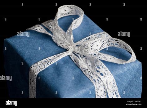 Closeup On White Lace Ribbon Bow Tied On Wrapped In Blue Textured Paper T On Black Background