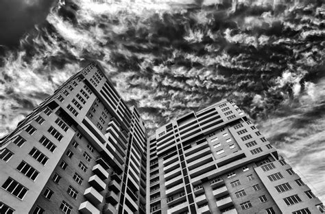 Black And White Photograph Of Two Tall Buildings With Clouds In The Sky