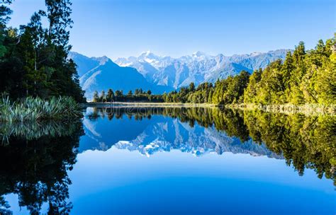 Perfect Reflection In Lake Matheson Surrounded By Beautiful Natural