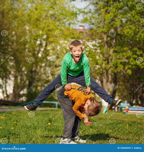 Two Cheerful Boys Play Outdoors Jump The Friend Through The Fri Stock