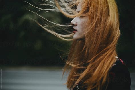 Portrait Of A Ginger Haired Young Woman With Hair Blowing In The Wind By Stocksy Contributor