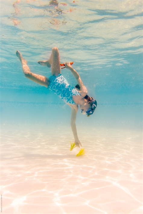 girl swimming underwater in blue swimming pool on vacation by stocksy contributor jp danko
