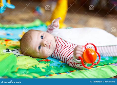 Cute Adorable Newborn Baby Playing On Colorful Toy Gym Stock Photo