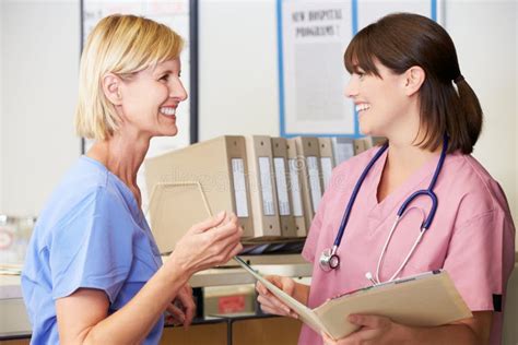 Two Nurses Discussing Patient Notes At Nurses Station Stock Photo