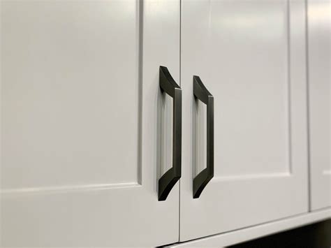 Two Black Handles On White Cabinets In A Kitchen