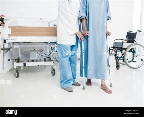 Low Section Of A Doctor Helping Patient In Crutches At The Hospital