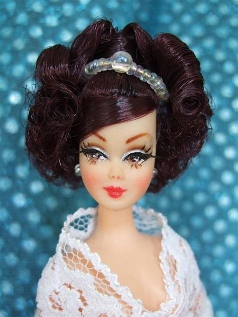 A Doll With Dark Hair Wearing A White Dress And Pearls On Its Head