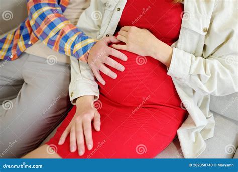 Happy Couple Is Resting On The Sofa At Home Beautiful Pregnant Woman And Her Husband Touching