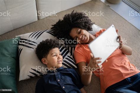 Brother And Sister Lying On The Floor Using Digital Tablet Together At