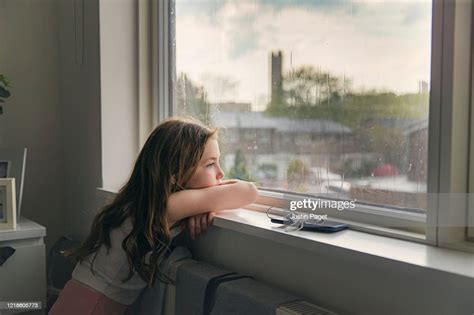 Young Girl Looking Out Of Window On A Rainy Day High Res Stock Photo