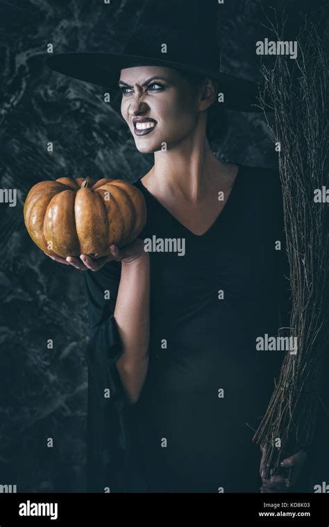 Halloween Witch Holding A Pumpkin And A Broom Stock Photo Alamy
