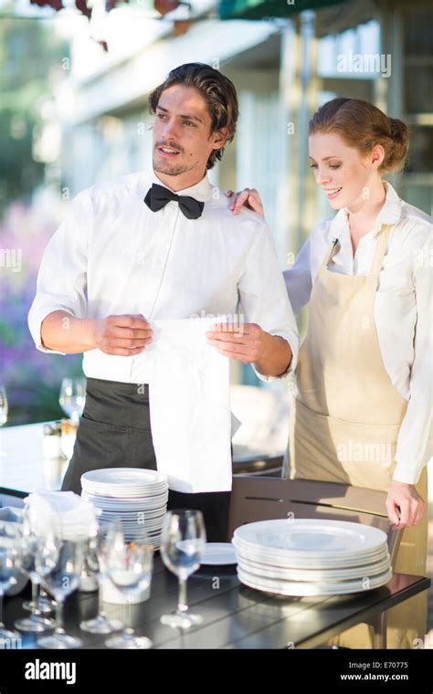 Waiter And Waitress Setting Up Tables In Patio Restaurant Stock Photo
