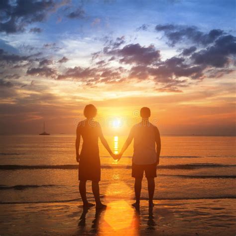 Happy Young Couple Holding Hands On Sea Beach During The Beautiful