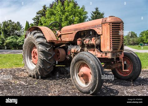 An Old Faded Red Case Tractor Sits On The Edge Of A Field Stock Photo