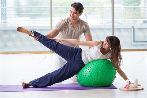 مدرب شخصي يساعد المرأة في صالة الألعاب الرياضية مع كرة الاستقرار صورة الخلفية والصورة للتنزيل