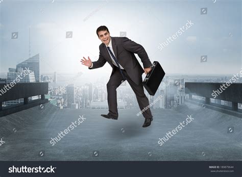 Cheerful Businessman In A Hurry Against Cityscape On The Horizon Stock